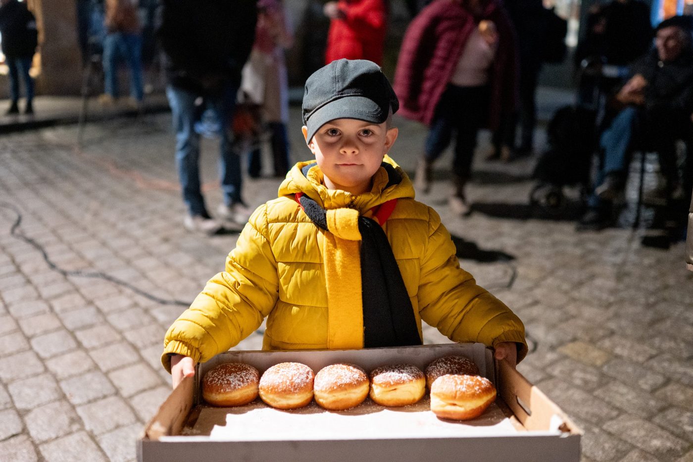 Kind mit einem Tablett voller Berliner (Sufganiyot) beim Chanukka-Abend
