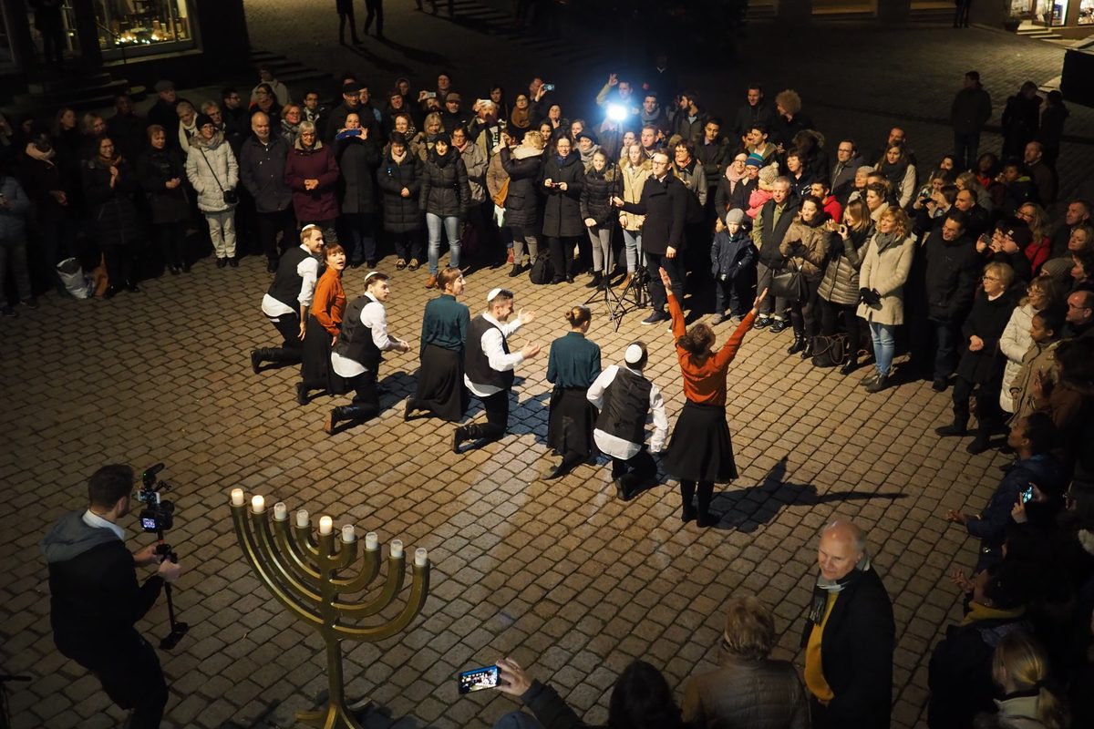 Tanzgruppe und Publikum um eine Chanukkia auf dem Tübinger Marktplatz